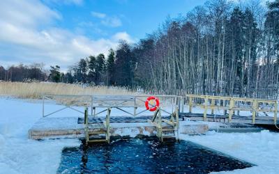 Lumen ympäröimä avanto, johon johtaa laituri. Taustalla metsää