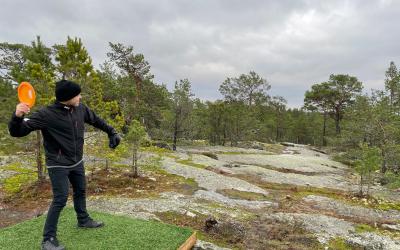 mies heittää frisbeegolfia kallioisessa metsässä