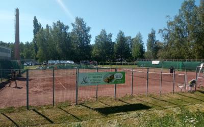 tenniskenttä aidan takana taustalla metsää