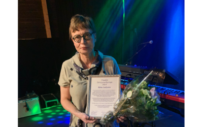 Vuoden terveystarkastajaksi 2024 valittu Riitta Laaksonen pitelee kunniakirjaa ja kukkakimppua.