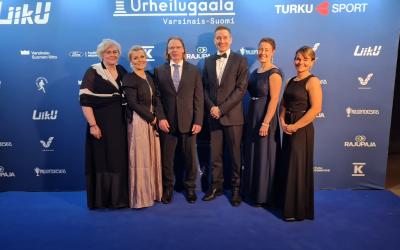 kuusi henkilöä poseeraa juhlavaatteissa urheilugaalassa