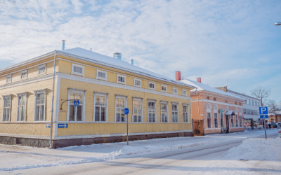vanhoja värikkäitä puutaloja talvisessa ja aurinkoisessa maisemassa.