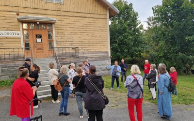 ihmisiä ulkona kuuntelemassa opasta.