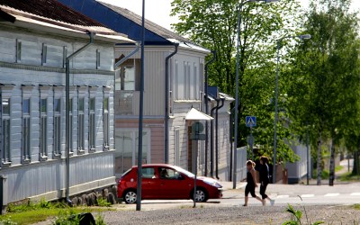 Kuvassa kaksi kävelijää ylittämässä suojatietä, risteyksessä on myös auto.