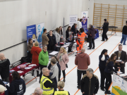 Ihmisiä sisäliikuntahallissa juttelemassa ja kulkemassa.