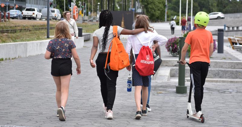 Neljä lasta kulkee yhdessä Uudenkaupungin kaupunginlahden rannalla.