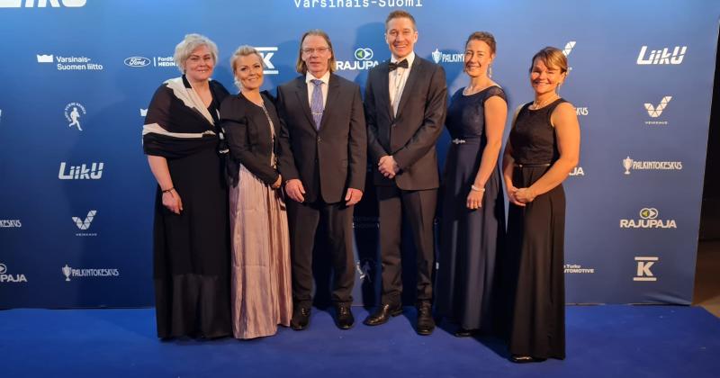 kuusi henkilöä poseeraa juhlavaatteissa urheilugaalassa