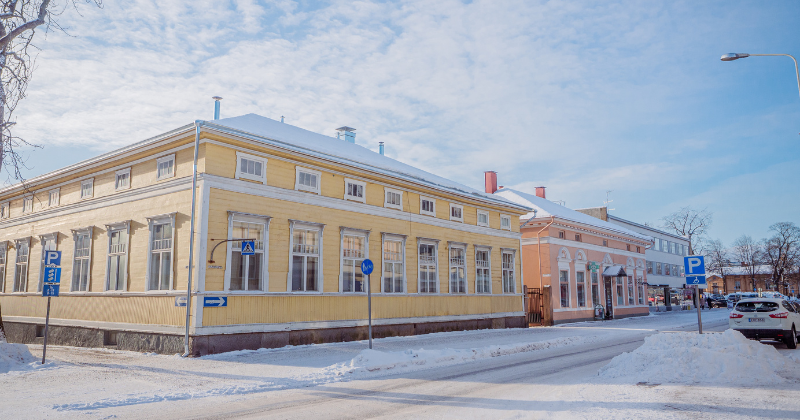 vanhoja värikkäitä puutaloja talvisessa ja aurinkoisessa maisemassa.