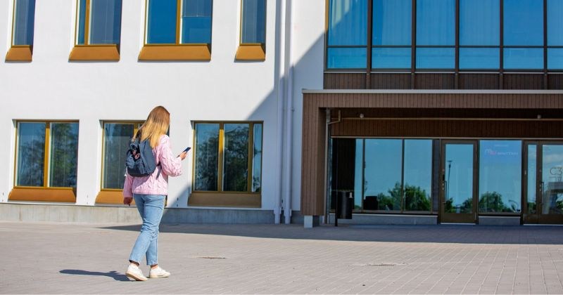 Nuori kävelee kohti Wintterin koulua ja katsoo kännykkää. 