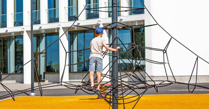 Lapsi kiipeää kiipeilytelineessä aurinkoisena kesäpäivänä.