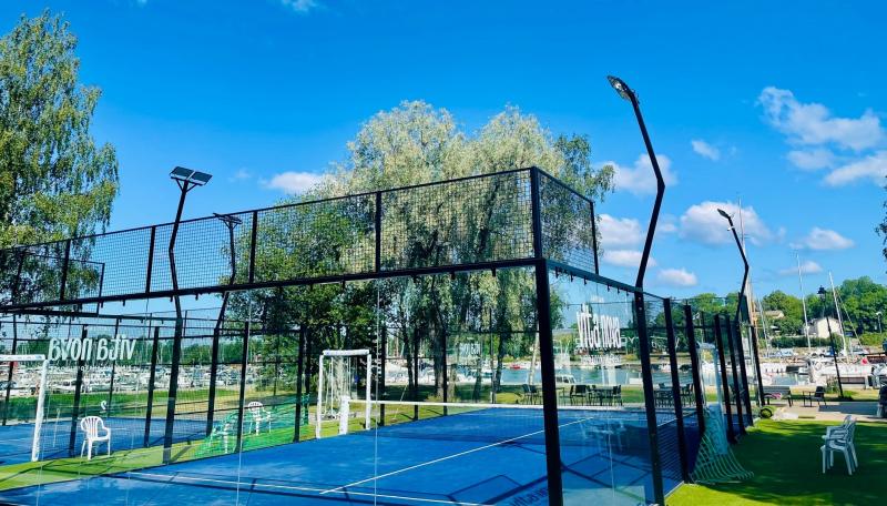 Padelkenttä ulkona taustalla puita ja kaupunginlahti veneineen